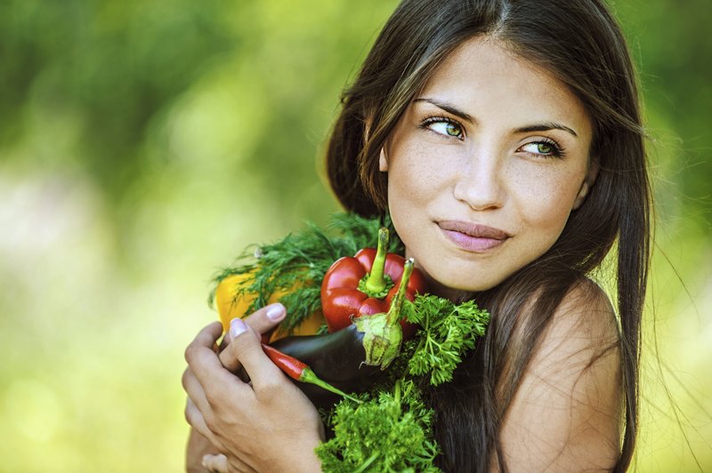 Healthy young woman holding vegetables